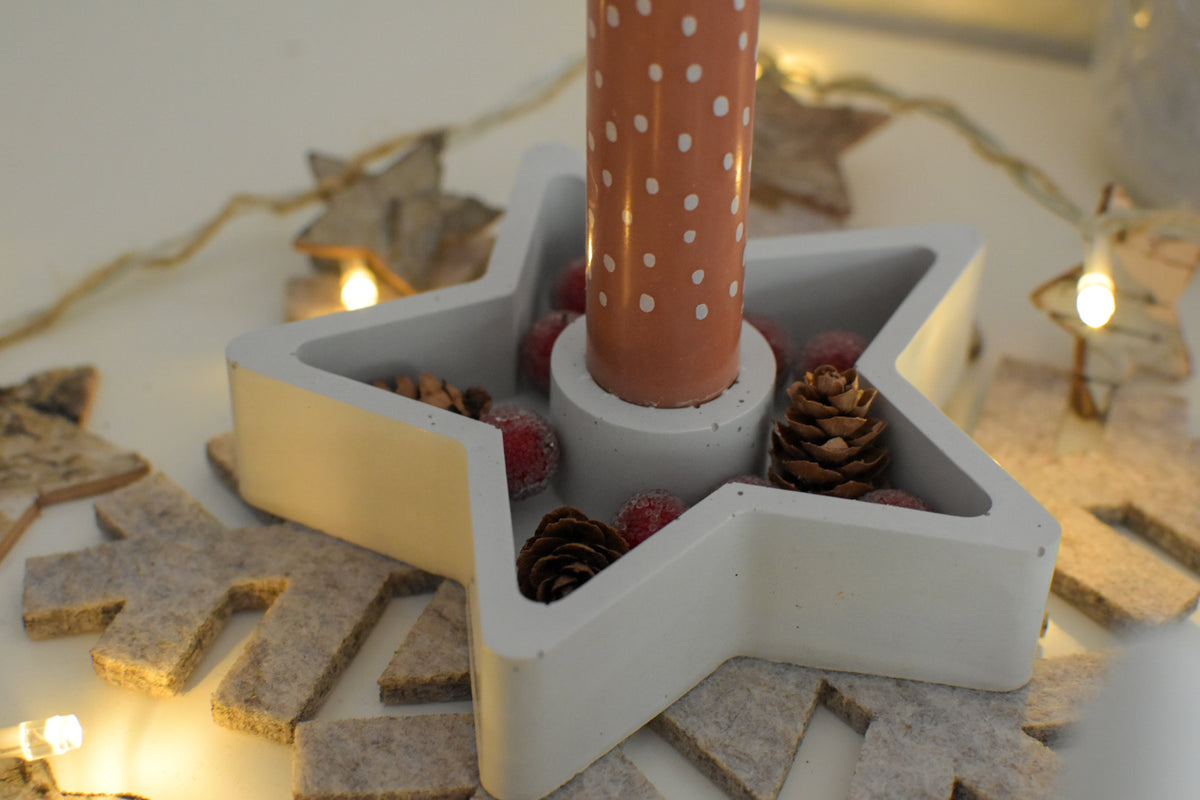 Kerzenhalter in Sternform aus Beton mit Stabkerze und Weihnachtsdeko