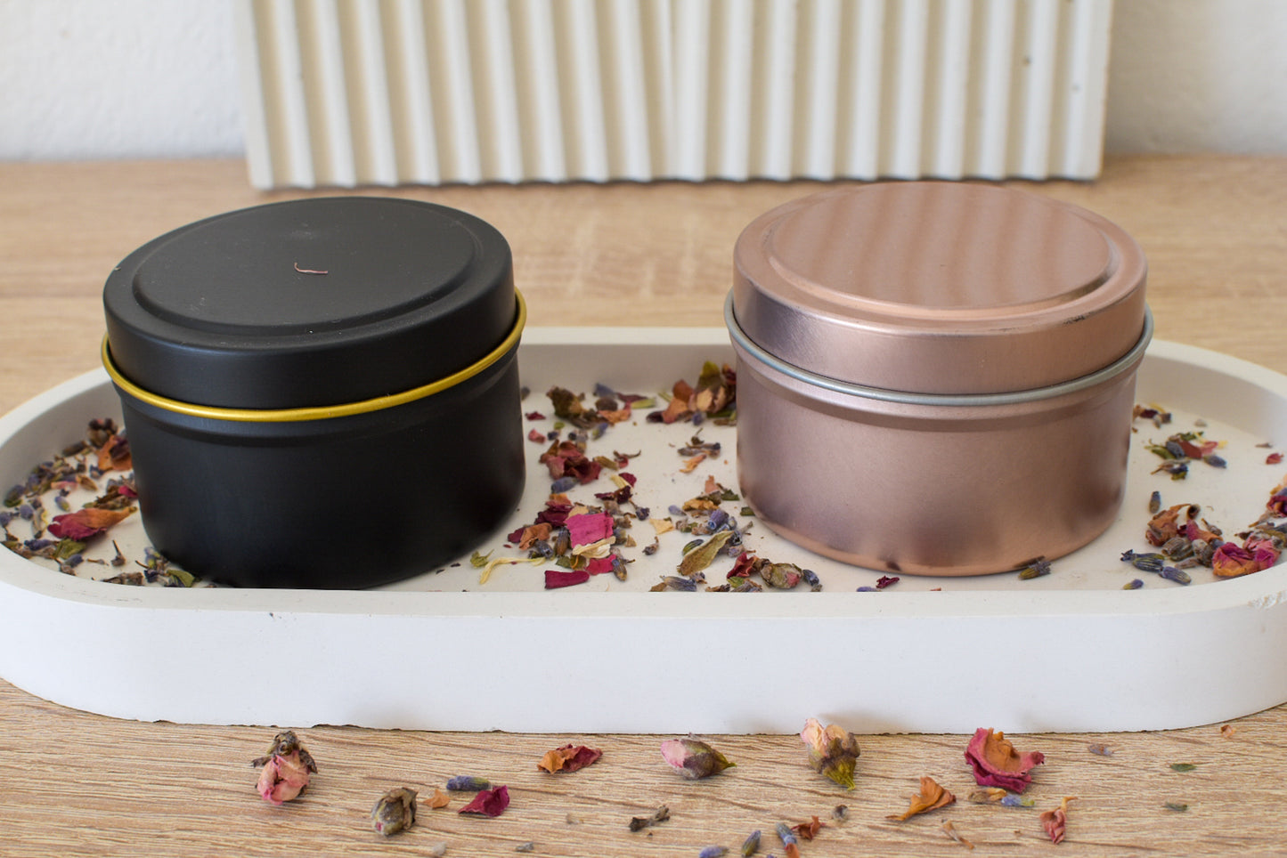 Schwarze und roséfarbene Duftkerzen in Dose auf Betontablett – minimalistische Tischdeko