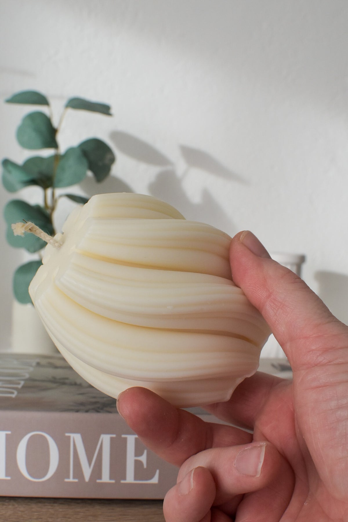 Swirl-Kerze aus Olivenwachs in der Hand, die geschwungenen Rillen im Detail