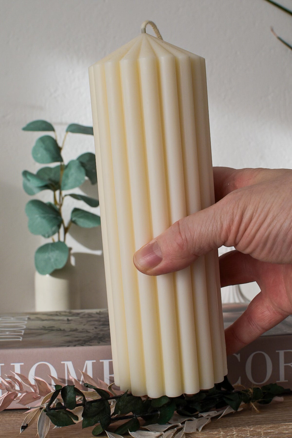 Große gerillte Stumpenkerze aus Olivenwachs in der Hand gehalten