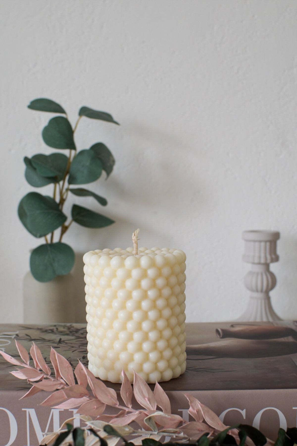 Bubble-Kerze Pearl aus Olivenwachs auf einem Buch mit Trockenblumen