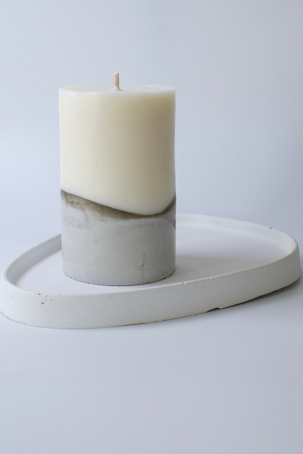 Kerze aus Olivenwachs mit Betonsockel auf einem weißen ovalen Tablett