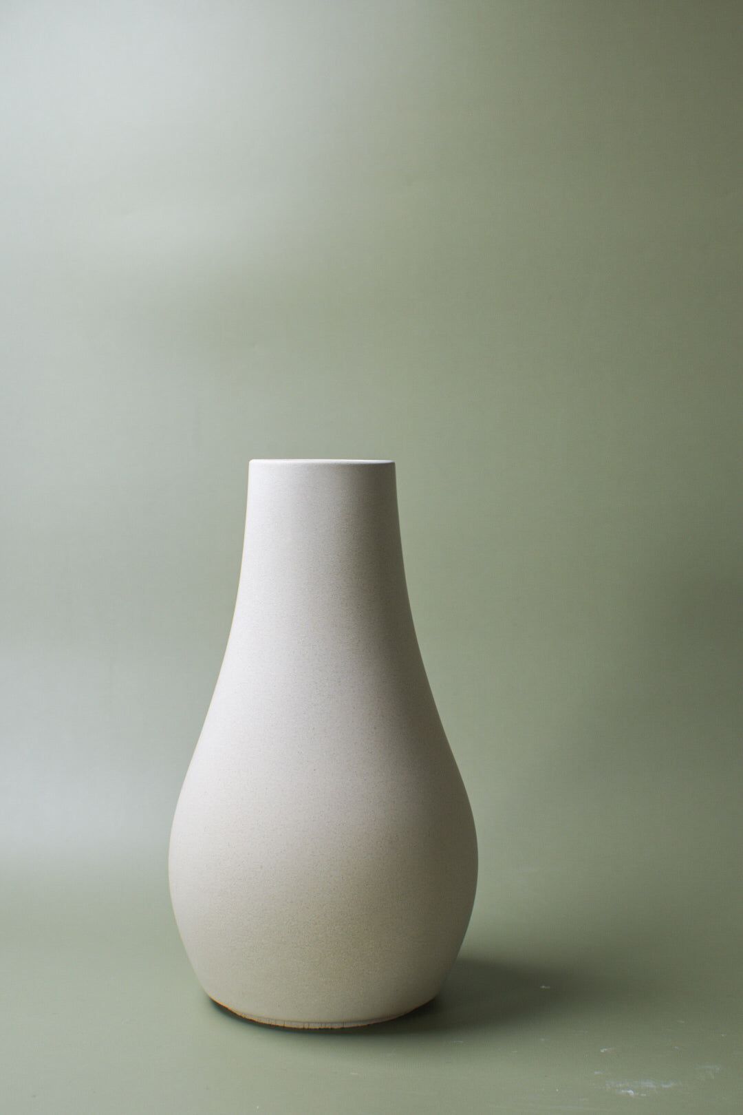 Kleine Vase aus Feinbeton vor salbeigrünem Hintergrund