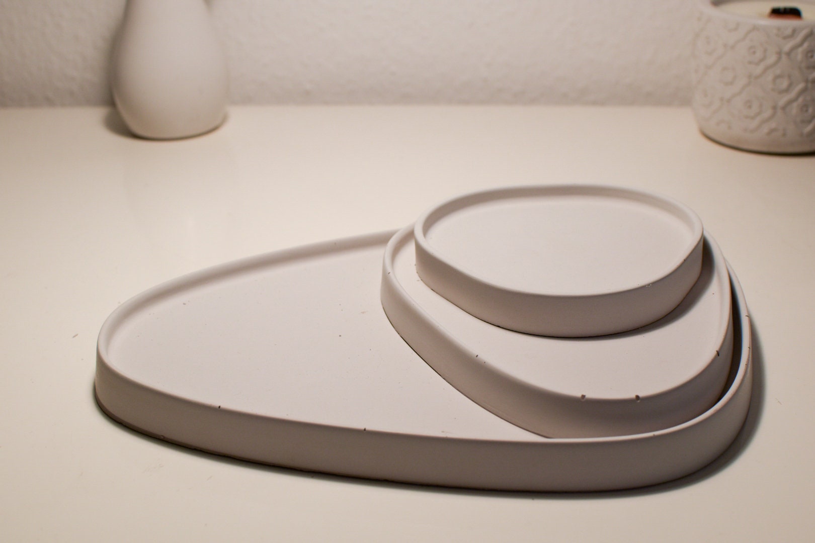 3 handgegossene Betontabletts in Eisgrau mit asymmetrischem Design – ideal als stilvolle Untersetzer oder lebensmittelecht versiegelte Ablage für trockene Lebensmittel.